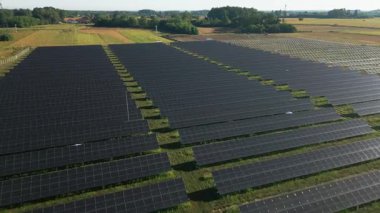 İnsansız hava aracı, sürdürülebilir ekonomik büyümenin önemli bir bileşeni olarak yenilenebilir enerji altyapısına yapılan yatırımların giderek artan eğilimini sembolize ederek, bir güneş çiftliğinin engin genişliğini yakalıyor. 