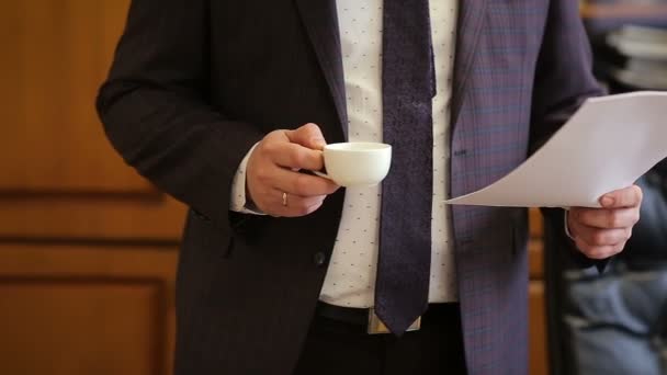 商人在办公室工作到很晚的时候, 从咖啡杯里阅读文件, 喝咖啡 — 图库视频影像