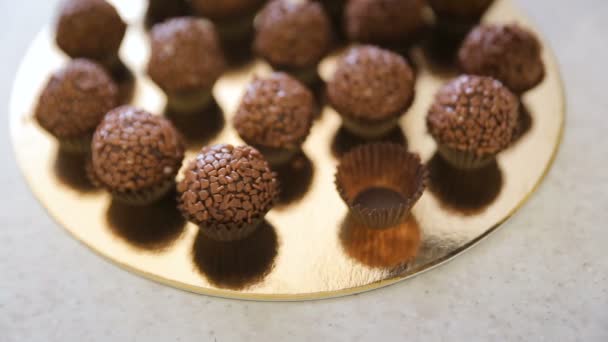 Chef is cooking chocolate balls in kitchen of restaurant indoors. Young woman roll pops in sprinkles with flakes — Stock Video