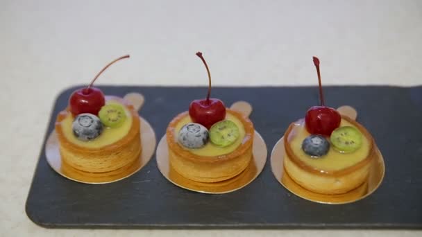 Eine Auswahl an Kirsch- und Zitronen-Cupcakes mit Honigglasur und Beeren — Stockvideo