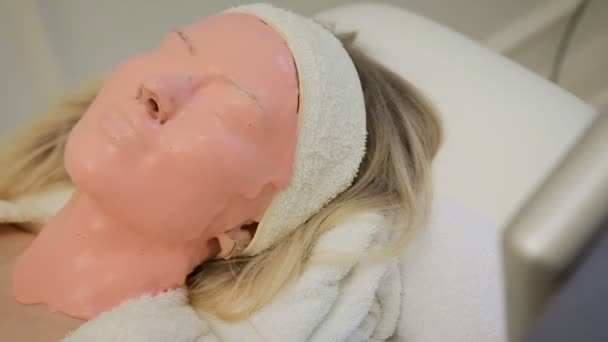 Hermosa mujer con máscara facial rosa en el salón de belleza. Tratamiento de spa . — Vídeo de stock
