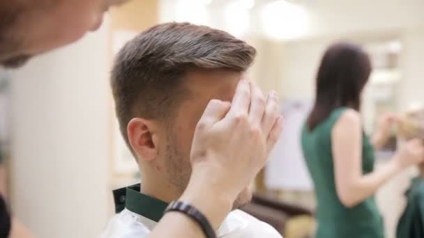 Cabeleireiros mãos no processo de trabalho. Barbeiro fazendo corte de cabelo de homem atraente no salão de beleza. Cabeleireiro no trabalho — Vídeo de Stock