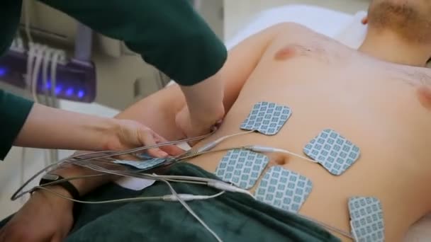 Elektrostatische massage procedure. Vrouwelijke arts bevestigen elektroden close-up op patiënten buik — Stockvideo