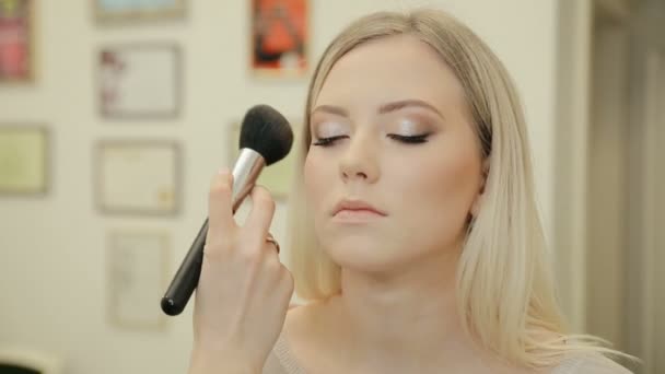 Mujer de belleza aplicando maquillaje. Hermosa chica aplicando cosmética con un cepillo grande. La chica se sonroja en los pómulos. Polvo, colorete . — Vídeos de Stock