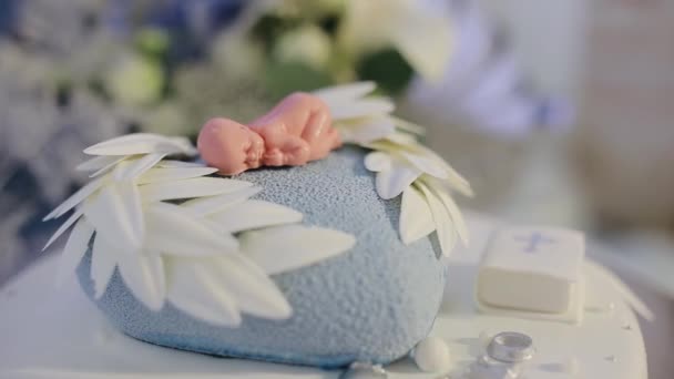 Decorated cake for newborn baby on table with baby doll decorated on top. Cake for christening event — Stock Video