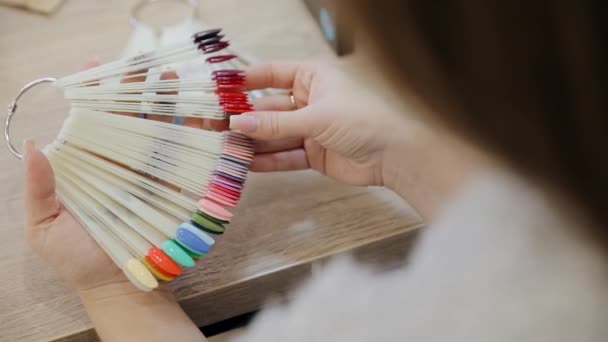 Échantillons de conception de main et ongles. Femme dans le salon de ongles choisir le design. Sélection de vernis à ongles couleur gomme laque. — Video