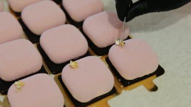 Şekerci, modern kremalı kekin üstüne pembe renkli kadife kremayla yenebilir altın renkli folyo süsü ekliyor. Zarif kare kadife kremalı pasta, fındık ve meyve dolu.