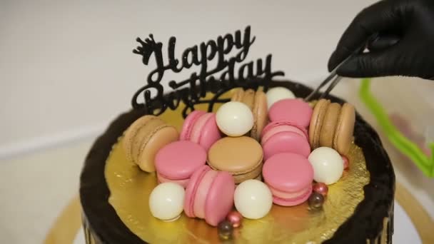 Pastel de chocolate cubierto con diferentes galletas de colores, macarrones y dulces para la fiesta de cumpleaños — Vídeo de stock