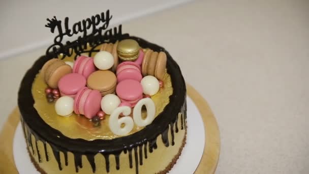 Decorare la torta con biscotti di macaron, caramelle e palline di cioccolato bianco per la festa di compleanno delle madri 60 anni — Video Stock