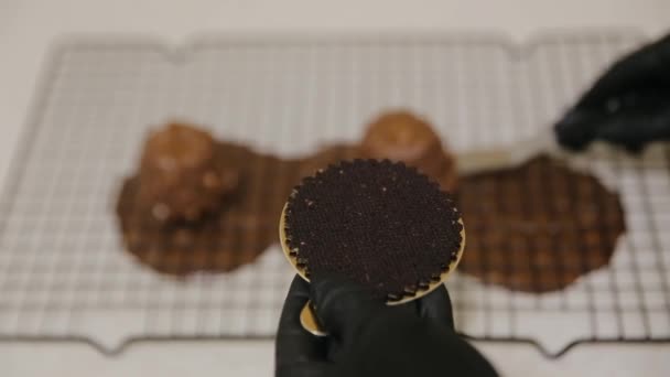 De banketbakker bereidt het dessert met gesmolten chocolade en gehakte pinda 's erop. Cake decoratie met chocolade glazuur. Snoepgoed — Stockvideo