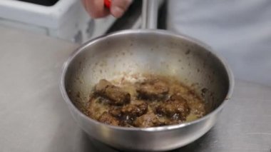 Şef mutfaktaki sıcak tavada alevi yavaş çekimde yakar, mutfakta büyük bir ateş, tavada ateş, açık ateşte pişirme. Şef tavada ciğer eti yakar, salata malzemesi.