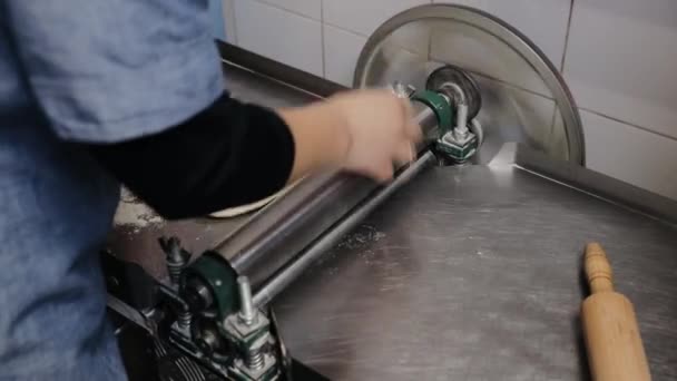 Chef-kok maakt deegbladerdeeg in de keuken. Baker vormgeven deeg gewalst gebak metalen werktafel closeup handen proces van het bereiden van brood khinkali deeg roller machine dunne pasta vel — Stockvideo