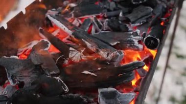 Barbekü ızgarasında yanan kömür. Sıcak kömür ve dumanlı alev. Yakın planda közlü barbekü. Alevler ve kırmızı közler. Restorandaki barbekü için yangın ve ızgara hazırlığı.