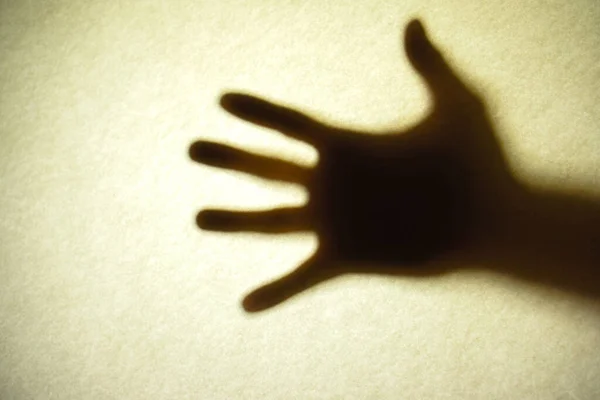 Buzlu camın arkasındaki adamın gölgeli elleri.