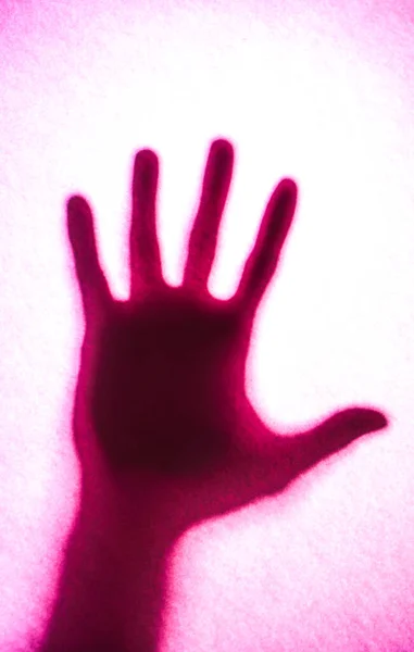 Buzlu camın arkasındaki adamın gölgeli elleri.