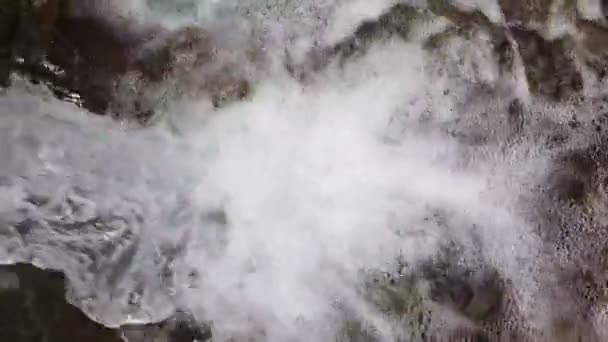 Fondo o textura. Movimiento lento de una pequeña cascada de montaña. El arroyo montañoso cae sobre las piedras en el fondo . — Vídeo de stock