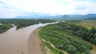 Büyük bir nehir üzerinde uçuş uçağı. Güzel dağlar arka plan üzerinde. Dağlar ve şiddetli bir kirli nehir su sel