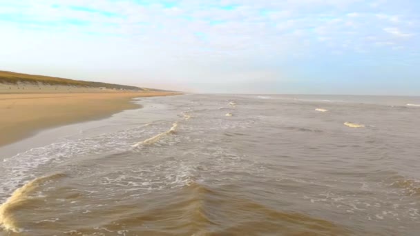 Luchtfoto. Slow motion vlucht over de zee en de golven die komen naar de wal in de zonnige ochtend. Nederland Zandvoort. Noordzee. Kustlijn — Stockvideo