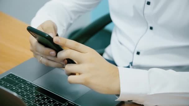 Közeli kép: egy üzletember kezét, aki dolgozik a telefon és a laptop az irodában — Stock videók