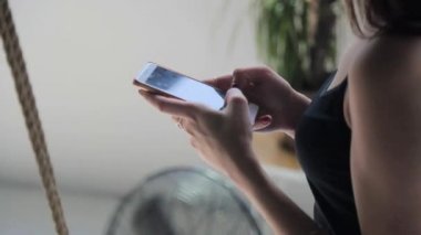 Kız beyaz iş. Salıncak odasında oturur ve bir cep telefonu ile çalışır