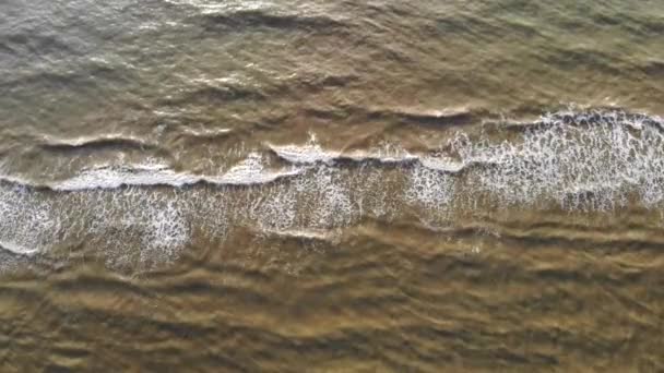 Luftaufnahme von oben. die Welle erreicht das Ufer und bricht über den Sand zusammen und tröpfelt das Meerwasser — Stockvideo