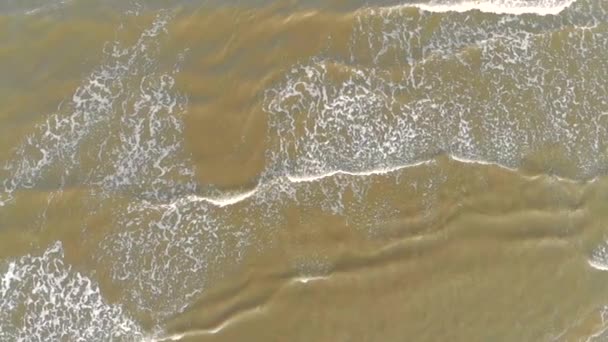 空中顶部视图。海浪到了岸边, 在沙地上破土动工, 海水变泥了 — 图库视频影像