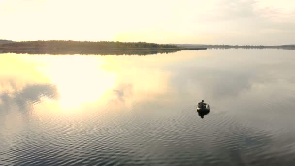Al atardecer, las rayas se reflejan en el agua que el pescador se sienta en el barco . — Vídeos de Stock
