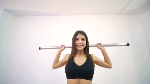 Close-up of a beautiful athlete looking at the camera, lifting the bar and smiling. — Stock Video