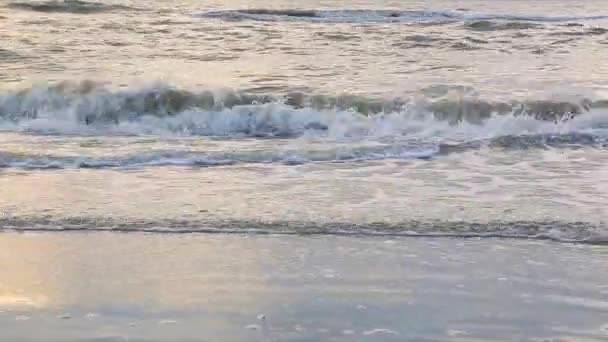 Onda chega perto da costa, o sol brilha na água. A onda do mar é lavada pela pitoresca costa de areia branca. Contexto ou textura — Vídeo de Stock