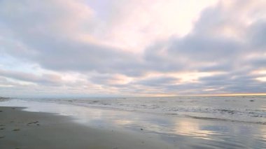 Kuzey Denizi'nde Panorama muhteşem günbatımı. Renkli bulutların sakin bir deniz sularında yansıtılır. Dalgalar yavaşça kıyıya gelin