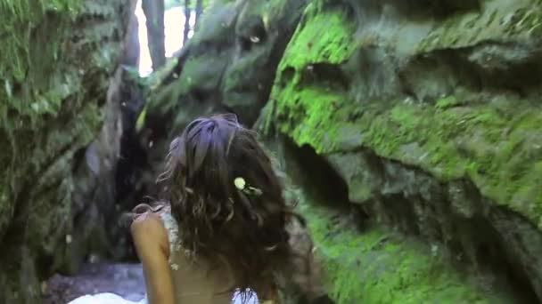 Carino sposa in un abito da sposa corre tra le rocce, e guarda la fotocamera con un grande sorriso. Volti felici, emozioni — Video Stock