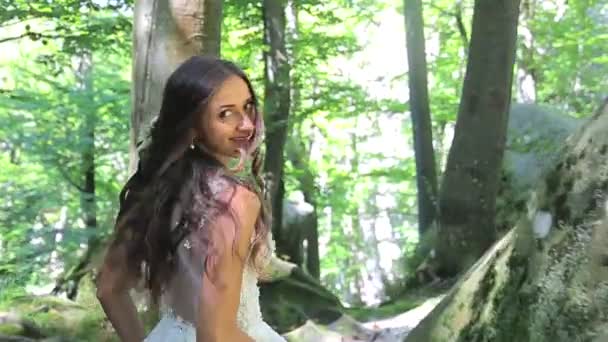 Schattig bruid in een trouwjurk loopt tussen de rotsen, en kijkt naar de camera met een grote glimlach. Gelukkige gezichten, emoties — Stockvideo