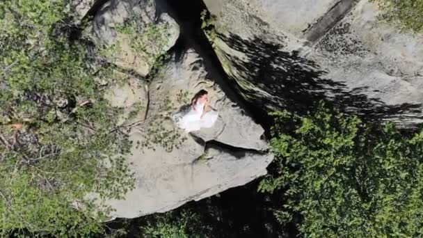 Imágenes aéreas, Bride está en el borde del abismo. Grandes acantilados rodean a la novia. La cámara vuela lentamente y vuela lejos de la novia — Vídeo de stock