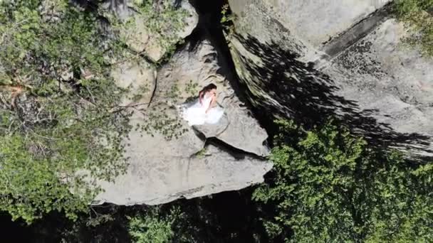 Imágenes aéreas, Bride está en el borde del abismo. Grandes acantilados rodean a la novia. La cámara vuela lentamente y vuela lejos de la novia — Vídeo de stock