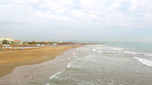 Timelapse пляж з туристів, що відпочивають, хвилі, швидко приходять до берега. Відпочиваючі ходити по жовтим піском, ходити на море. Валенсія пляж — стокове відео