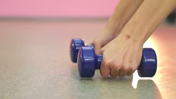 Женские руки крупным планом поднять два синих гантели в тренажерном зале для фитнеса — стоковое видео