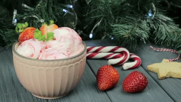 Helado para el nuevo año. Una buena composición de helado y fresas en el fondo de un árbol de Navidad — Vídeo de stock