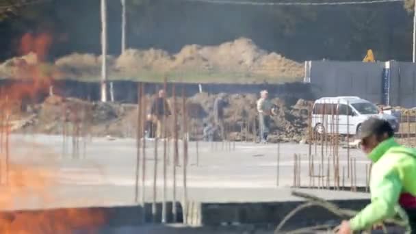 Sfondo costruzione offuscata. un cantiere dove viene bruciata la spazzatura in fiamme, i lavoratori si spostano sul cantiere — Video Stock