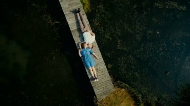 Havadan görünümü üstte. Gençlerin iki sevgili ahşap bir köprüde yalan. Genç bir çift etrafında bir peri masalı. Mutlu genç çift.