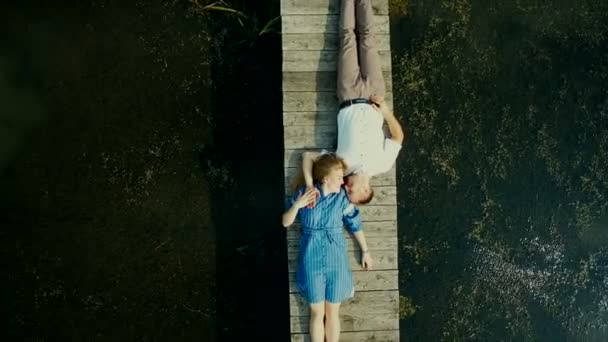 Aerial view on top. Two lovers of young people lie on a wooden bridge. Fairy tale around a young couple. Happy young couple. — Stock Video