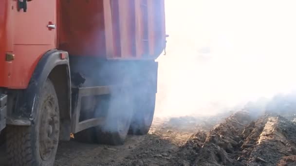 Um caminhão que viaja ao longo do canteiro de obras, criando muita fumaça — Vídeo de Stock