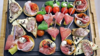 Ziyafet tablonun arka plan. Açık büfe masada sandviç kanepeler. Mozzarella peyniri ile otlar ve sosis ekmek ile kırmızı domates