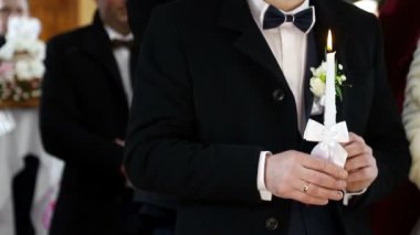 Damat kilisede bir mum tutan. Hıristiyanlık düğün töreni.