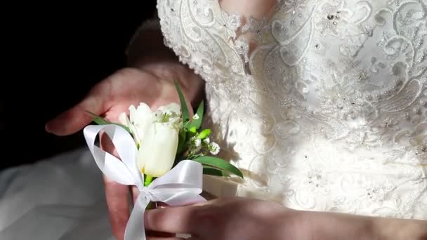 A menyasszony tart egy virág Boutonniere a kezében, és azt mutatja. A nap sugarai esik a menyasszony test és a virág — Stock videók