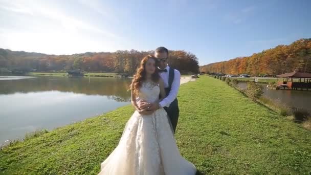 湖の近くの公園で花嫁ダンス。晴れた日とこれらの素晴らしい花嫁ダンス壮大な湖の近くの橋の上 — ストック動画