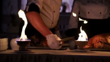 Garsonlar et parçalarını dilim. Et garsonlar kesme aydınlatır yangın kase. Şef aşçılar izleyiciler için et
