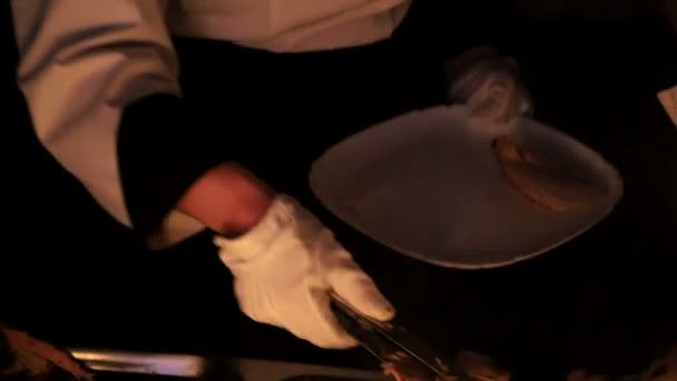 Le serveur coupe la viande. Capturer une caméra à travers un feu 