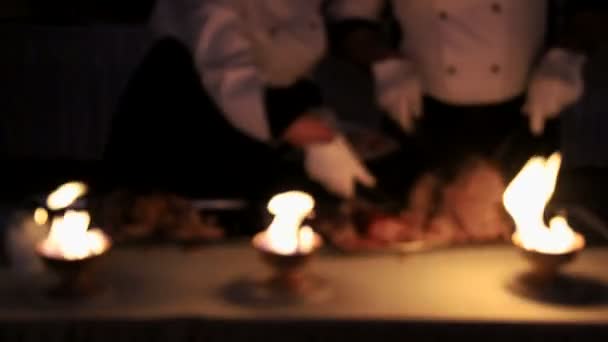 Číšníci nakrájet kousky masa. Misku ohně, která zesvětluje bourání masa číšníci. Šéfkuchař vaří maso na diváky — Stock video