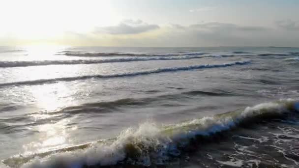 De beweging van de camera voor de golven van de zee. De ochtendzon schijnt in de camera en wordt weerspiegeld in het water. Gedaald tot 4k — Stockvideo