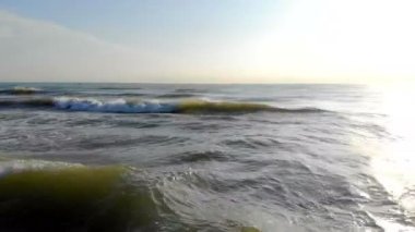 Dalgalar deniz önünde kamera hareket. Sabah güneşi kamerada parlar ve suda yansıtılır. 4 k için düştü